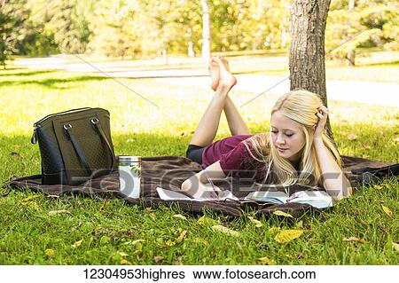 Stock Photograph - A young woman spending personal time in Bible study outdoors in a park in autumn; Edmonton, Alberta, Canada. Fotosearch