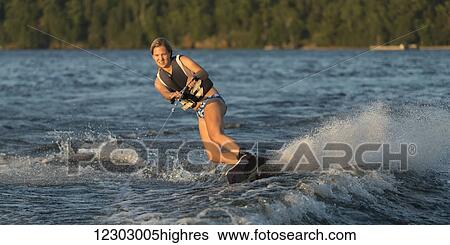 Stock Photograph - A young woman wakeboarding on a lake; Ontario, Canada. Fotosearch