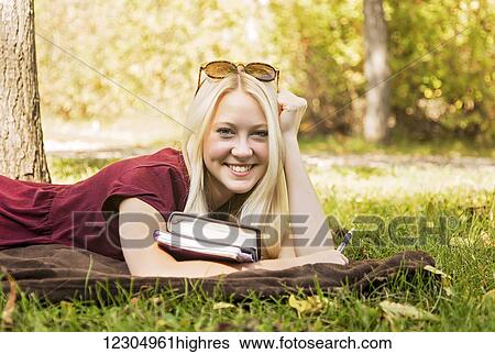 A young woman with long blond hair spending personal time in Bible study outdoors in a park in autumn and posing for the camera; Edmonton, Alberta, Canada View Large Photo Image Stock Photograph - A young woman with long blond hair spending personal time in Bible study outdoors in a park in autumn and posing for the camera; Edmonton, Alberta, Canada. Fotosearch