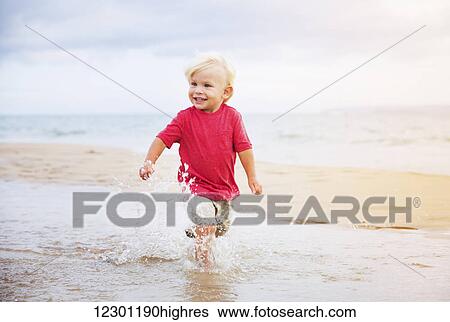 Stock Photograph - Adorable cute young boy running on the beach. Fotosearch