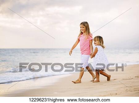 Adorable Young Sisters, Two Little Girls Walking together on the Beach at Sunet, Family Lifestyle. View Large Photo Image Stock Photograph - Adorable Young Sisters, Two Little Girls Walking together on the Beach at Sunet, Family Lifestyle.. Fotosearch