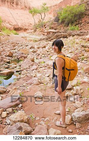 Stock Image - Adventurer exploring a desert canyon narrows, Capitol Reef National Park; Utah, United States of America. Fotosearch