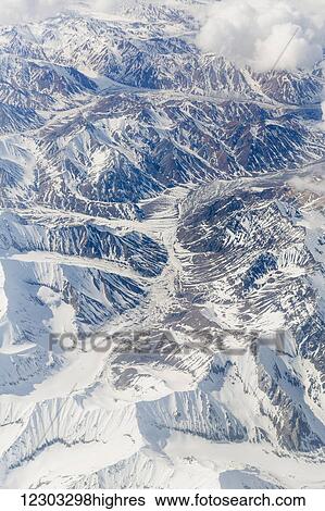Stock Photograph - Aerial view of a river valley surrounded by snow capped mountains, Alaska Range, Interior Alaska, USA, Winter. Fotosearch