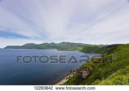 Stock Image - Aerial view of rocky cliffs and green bluffs along the shore of Popof Island near Sand Point, Southwestern Alaska, USA, Summer. Fotosearch