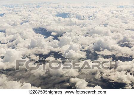 Aerial view of scattered clouds, snow covered peaks rising above the clouds in the background; Alaska, United States of America View Large Photo Image Stock Photograph - Aerial view of scattered clouds, snow covered peaks rising above the clouds in the background; Alaska, United States of America. Fotosearch