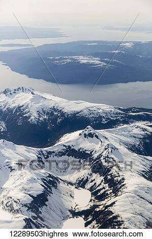 Stock Photograph - Aerial view of snow capped mountains above the city of Ketchikan, Southeast Alaska, USA, Winter. Fotosearch
