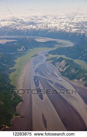 Stock Photography - Aerial view of snow-capped peaks surrounding a green river valley, Aleutian Range, Alaska Peninsula, Southwestern Alaska, USA, Summer. Fotosearch