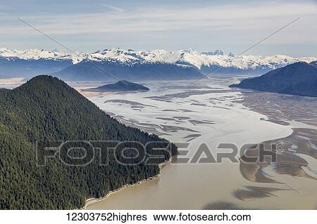 Stock Photograph - Aerial view of Woronkofski Island along the Stikine River Delta, low tide revealing mud flats below the snow capped peaks in the background; Wrangell, Alaska, United States of America. Fotosearch
