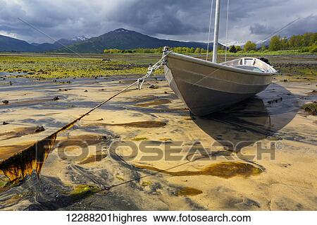 Stock Photograph - Aluminum skiff settles in sand at low tide in Womens' Bay, Kodiak, Alaska. Fotosearch