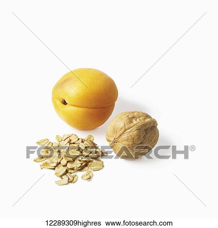 Stock Photograph - An apricot, walnut and oats on a white background; Toronto, Ontario, Canada. Fotosearch