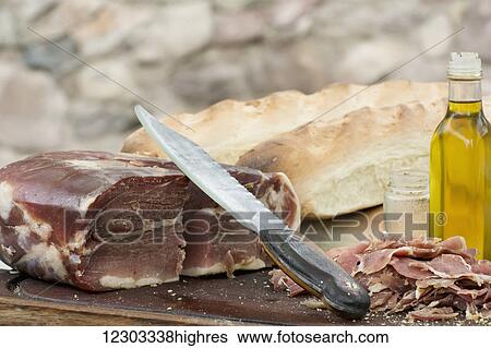 An outdoor scene of a knife is resting on top of a block of prosciutto with bread and olive oil; Mendoza, Argentina View Large Photo Image Stock Photograph - An outdoor scene of a knife is resting on top of a block of prosciutto with bread and olive oil; Mendoza, Argentina. Fotosearch