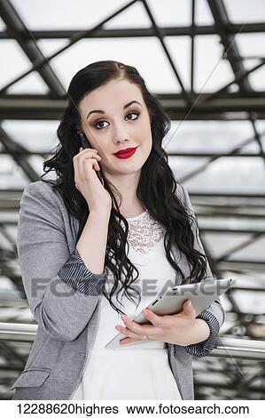 Attractive young millennial business woman on her cell phone in downtown office building; Edmonton, Alberta, Canada View Large Photo Image Stock Photograph - Attractive young millennial business woman on her cell phone in downtown office building; Edmonton, Alberta, Canada. Fotosearch