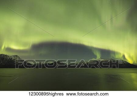 Stock Photograph - Aurora Borealis dancing above the Chugach Mountains and Turnagain Arm, Kenai Peninsula, Southcentral, Alaska. Fotosearch