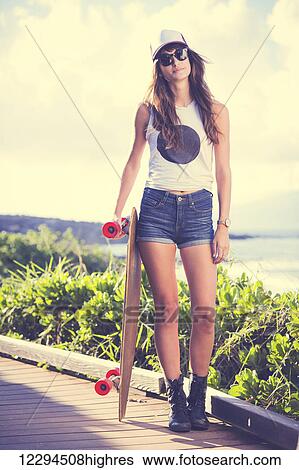 Stock Photograph - Beautiful hipster girl with skate board wearing sunglasses. Fotosearch