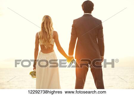 Stock Photograph - Beautiful Sunset Wedding. Bride and Groom at Sunset. Fotosearch