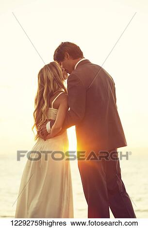 Stock Photograph - Beautiful Sunset Wedding. Bride and Groom at Sunset. Fotosearch