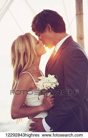 Beautiful Sunset Wedding by the Sea. Bride and Groom Kissing at Sunset. Romantic Married Couple. View Large Photo Image Stock Photograph - Beautiful Sunset Wedding by the Sea. Bride and Groom Kissing at Sunset. Romantic Married Couple.. Fotosearch