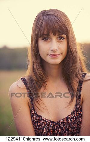 Stock Photograph - Beautiful woman in golden field at sunset, Fashion lifestyle, Vibrant color, Backlit warm tones. Fotosearch
