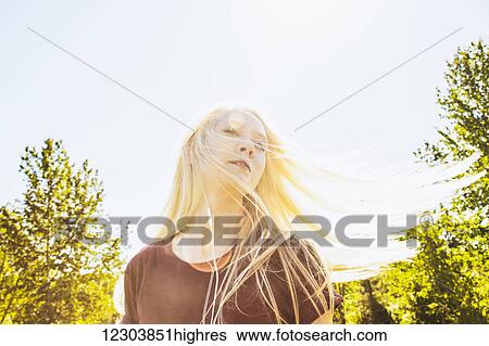 Beautiful young woman listening to music and singing along while swinging her long, blond hair outdoors in a city park; Edmonton, Alberta, Canada View Large Photo Image Stock Photograph - Beautiful young woman listening to music and singing along while swinging her long, blond hair outdoors in a city park; Edmonton, Alberta, Canada. Fotosearch