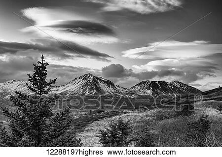 Stock Photograph - Black and white photo of lenticular clouds over the Three Sisters mountains, Kodiak Island, Southwest Alaska. Fotosearch