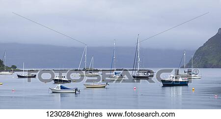 Stock Photograph - Boats moored in a tranquil Portree harbour; Skye Island, Scotland. Fotosearch