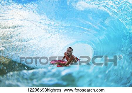 Stock Photograph - Body Boarder on Large Wave Surfing in the Tube Getting Barreled. Fotosearch