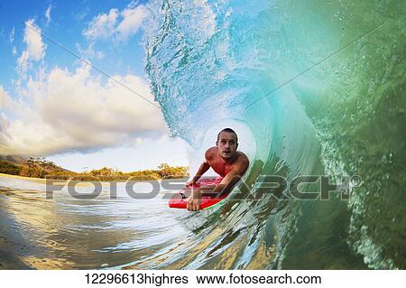 Stock Photograph - Body Boarder on Large Wave Surfing in the Tube Getting Barreled. Fotosearch