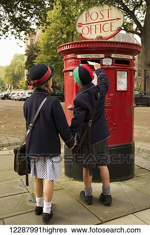 Stock Photograph - Brother and sister holding hands posting letter; London, England. Fotosearch