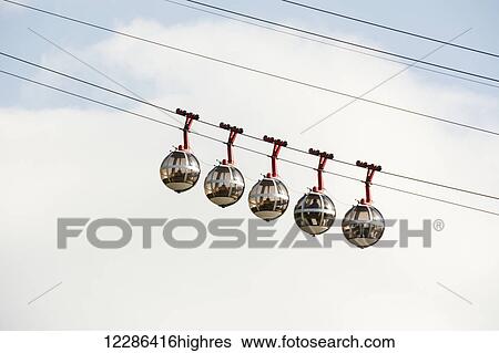 Stock Photograph - Bubble gondola against blue sky and white cloud; Grenoble, France. Fotosearch