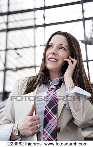 Business woman on an escalator talking on her cell phone and holding a tablet; Edmonton, Alberta, Canada View Large Photo Image Stock Photograph - Business woman on an escalator talking on her cell phone and holding a tablet; Edmonton, Alberta, Canada. Fotosearch