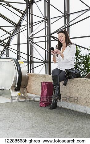Business woman texting on her smart phone after taking a shopping break during her work day; Edmonton, Alberta, Canada View Large Photo Image Stock Photograph - Business woman texting on her smart phone after taking a shopping break during her work day; Edmonton, Alberta, Canada. Fotosearch