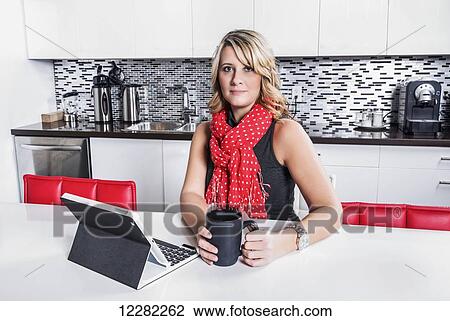 Stock Image - Businesswoman taking a coffee break and checking her tablet; St. Albert, Alberta, Canada. Fotosearch