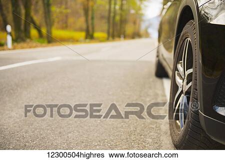Stock Photograph - Car on a road with autumn coloured trees; Ascona, Ticino, Switzerland. Fotosearch