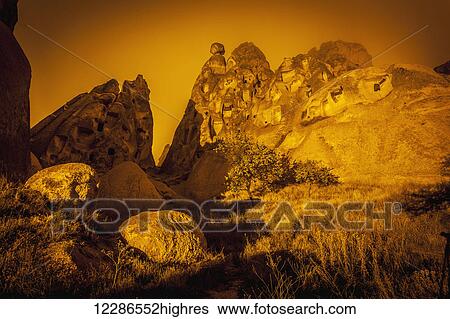 Stock Photograph - Cave homes in rock formations and fairy chimneys; Goreme, Cappadocia, Turkey. Fotosearch