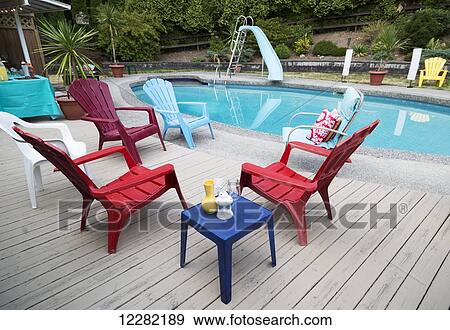 Chairs on a deck beside a swimming pool; Surrey, British Columbia, Canada View Large Photo Image Stock Photo - Chairs on a deck beside a swimming pool; Surrey, British Columbia, Canada. Fotosearch