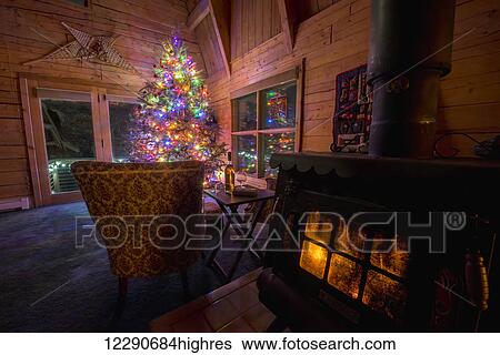 Stock Photograph - Christmas setting in a log home with a toasty wood burning stove.. Fotosearch