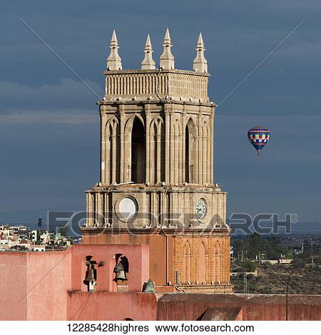 Clock tower and bells of the parish church with a hot air balloon flight in the distance; San Miguel de Allende, Guanajuato, Mexico View Large Photo Image Stock Photograph - Clock tower and bells of the parish church with a hot air balloon flight in the distance; San Miguel de Allende, Guanajuato, Mexico. Fotosearch
