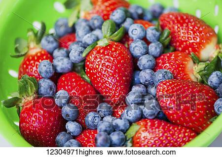 Stock Photograph - Close up of a strainer with strawberries and blueberries. Fotosearch
