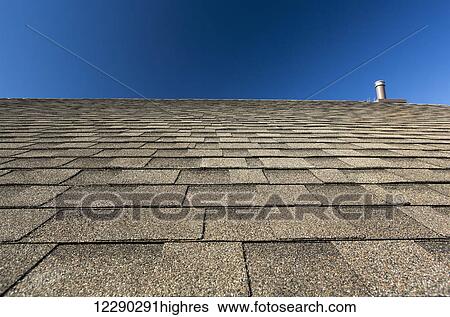 Stock Photograph - Close up of brand new roof shingles with intersting lines and blue sky; Calgary, Alberta, Canada. Fotosearch