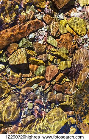 Close up of colourful creek stones underwater with ripples in water; Waterton, Alberta, Canada View Large Photo Image Stock Photograph - Close up of colourful creek stones underwater with ripples in water; Waterton, Alberta, Canada. Fotosearch