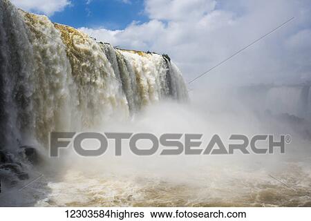 Stock Photograph - Cloud of spray beneath sunny Iguazu Falls; Parana, Brazil. Fotosearch