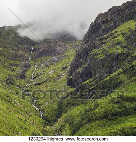 Clouds lying low over rugged and foliage covered mountains; Scotland View Large Photo Image Stock Photograph - Clouds lying low over rugged and foliage covered mountains; Scotland. Fotosearch