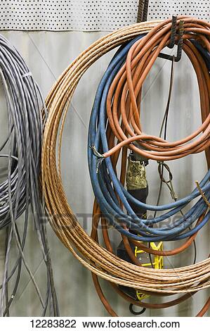 Stock Image - Coils of cable and cord hanging on a wall at an electrical power plant, Sand Point, Southwestern Alaska, USA. Fotosearch