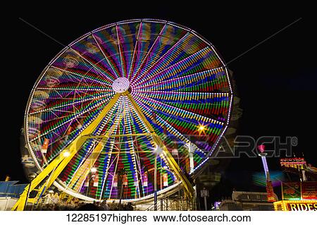 Stock Photograph - Colourful lights of a moving ferris wheel at nighttime; Calgary, Alberta, Canada. Fotosearch