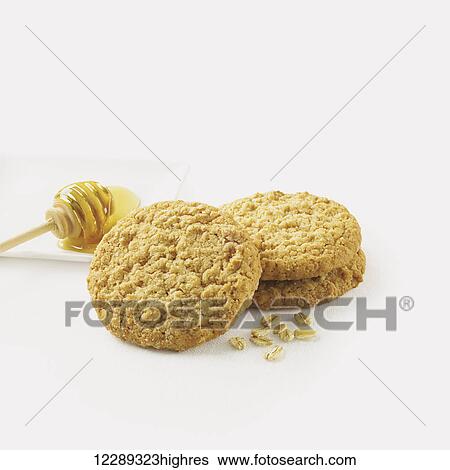 Stock Photograph - Cookies with honey and oats on the side against a white background; Toronto, Ontario, Canada. Fotosearch