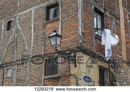Corner of a brick building with a light mounted to the wall and fabric hanging from a window; San Sebastian, Spain View Large Photo Image Stock Photo - Corner of a brick building with a light mounted to the wall and fabric hanging from a window; San Sebastian, Spain. Fotosearch