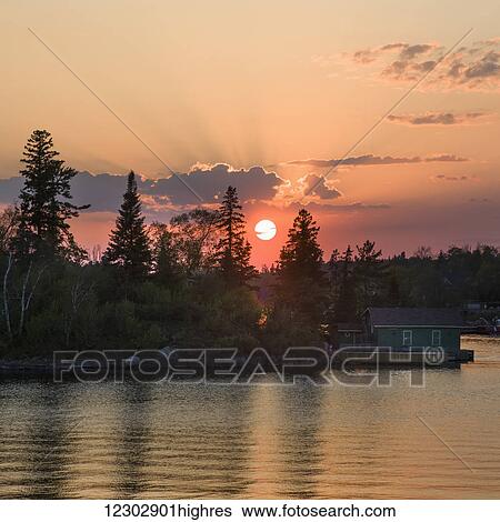 Cottage on the edge of a lake at sunrise with a pink sky, Lake of the Woods; Kenora, Ontario, Canada View Large Photo Image Stock Photograph - Cottage on the edge of a lake at sunrise with a pink sky, Lake of the Woods; Kenora, Ontario, Canada. Fotosearch