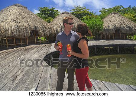 Couple on a wooden boardwalk with refreshing drinks at Saint Georges Caye Resort; Belize City, Belize View Large Photo Image Stock Photograph - Couple on a wooden boardwalk with refreshing drinks at Saint Georges Caye Resort; Belize City, Belize. Fotosearch