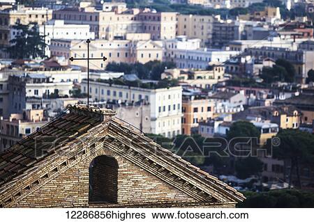 Stock Photograph - Cross on peaked roof of a building and cityscape; Rome, Italy. Fotosearch