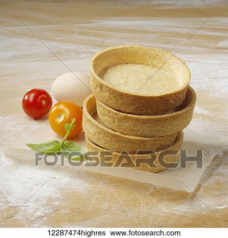 Stock Photograph - Dessert cups in a pile on a floured surface with cherry tomatoes, egg and mint leaves; Toronto, Ontario, Canada. Fotosearch
